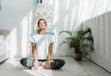 Beautiful Happy Girl With Closed Eyes Practicing Yoga In Lotus Position In Bedroom In The Morning