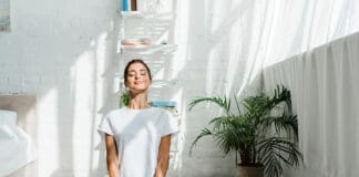 Beautiful Happy Girl With Closed Eyes Practicing Yoga In Lotus Position In Bedroom In The Morning