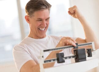 Excited Man Clenching Fist While Using Weight Scale