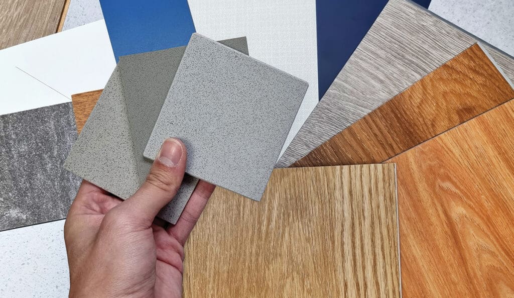 Interior Designer's Hand Holding Quartz Stone Samples Matching Color With Wood Vinyl Flooring Tiles, Engineering Wood Tiles, Stone Tiles, Solid Color Laminateds, Artificial Stone Tiles. Close Up View.