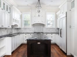 A Beautiful Kitchen With White Cabinets And Black Countertops.