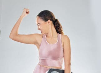 Scale, Success And Strong Woman With Fitness, Lose Weight Progress And Body Goals Or Fist, Power And Bodybuilder. Sports Person Or Model For Achievement, Diet And Yes Sign On Studio, White Background