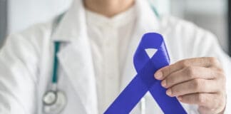 Dark Blue Ribbon For Colon Colorectal Cancer Awareness On Medical Doctor's Hand Support