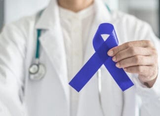 Why Everyone Needs to Talk about Colorectal Cancer Screening at 45 Dark Blue Ribbon For Colon Colorectal Cancer Awareness On Medical Doctor's Hand Support