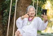 Elderly Woman Relaxing On A Swing While Using A Tablet In A Serene Outdoor Setting
